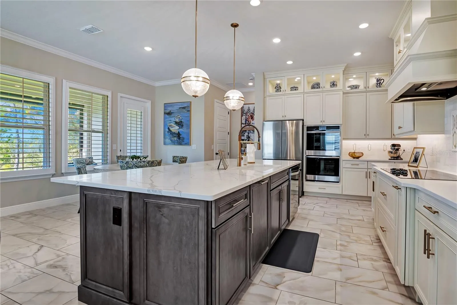 Designer kitchen with stacked cabinetry, illuminated upper display cabinets and built-in stainless steel appliances.