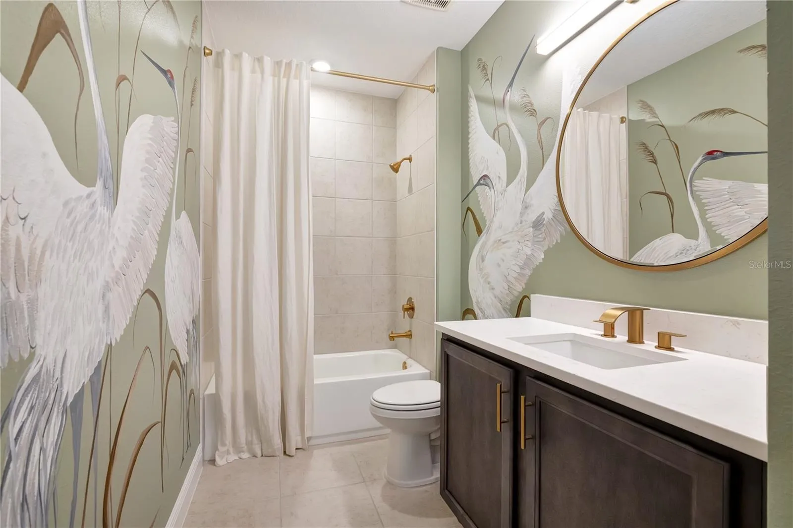 Beautifully styled bathroom featuring a bird-pattern accent wall, upgraded vanity and tub with shower.