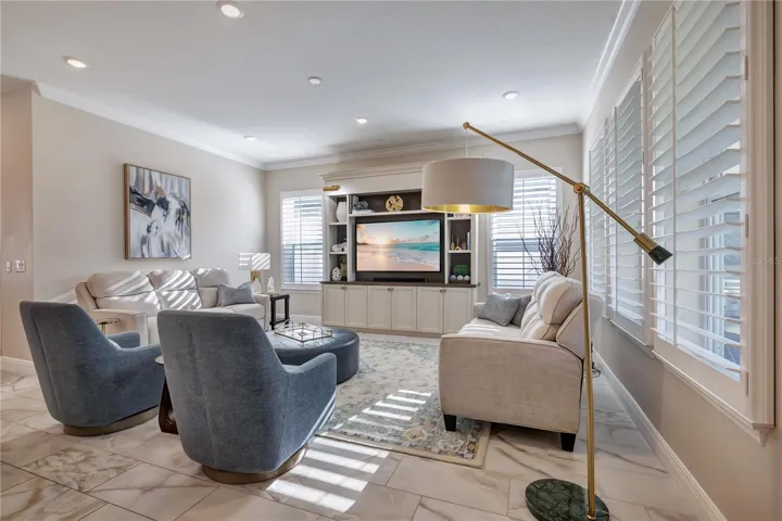 Inviting family room featuring crown molding, recessed lighting and plantation shutters.