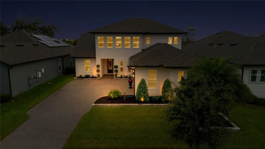 Elevated evening view highlights the front entrance, driveway and landscape lighting.