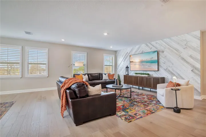 Spacious loft featuring a statement accent wall, recessed lighting and plantation shutters.