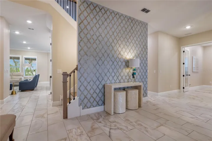 Statement accent wall highlights the entryway, with an open staircase and views into the main living areas.