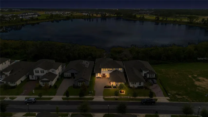 Wide twilight aerial captures the property, neighboring homes and lake setting.