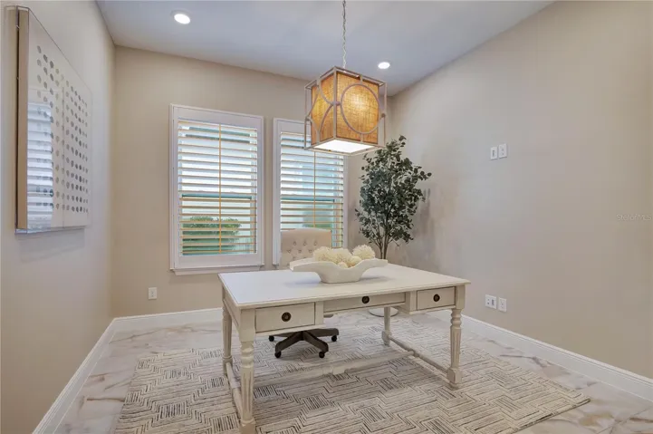 Dedicated office featuring plantation shutters, recessed lighting and a decorative pendant fixture.