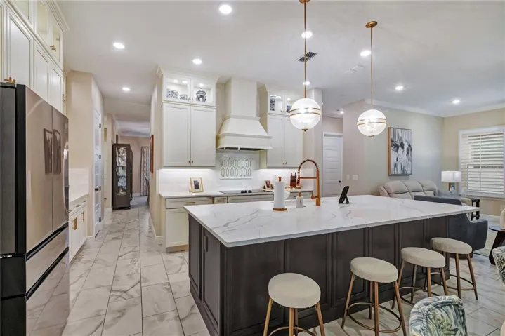 Upgraded kitchen featuring an oversized island with seating, contrasting cabinetry and designer pendant lighting.