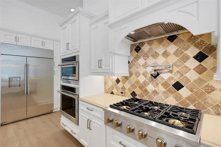 The chef's kitchen features hi-end appliances that includes a 6-burner gas cooktop, oversized built-in refrigerator, built-in ovens and warming drawer . . .