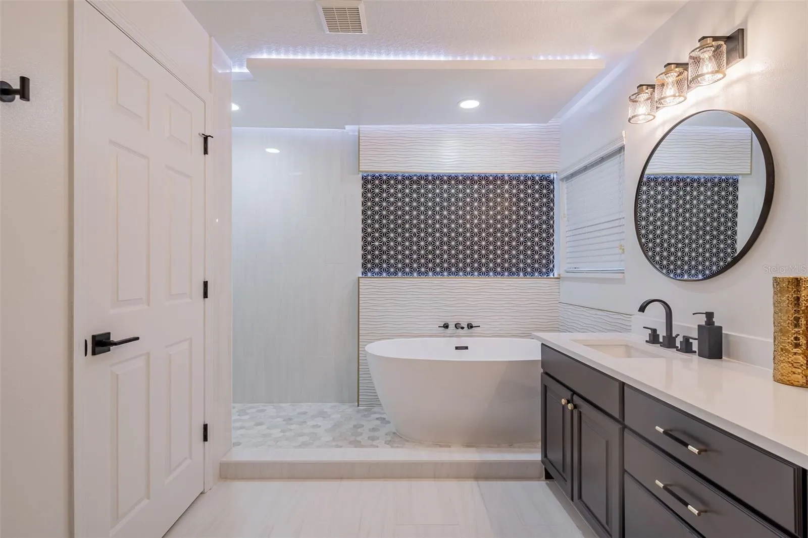 Completely gutted and rebuilt in 2022 with an investment of approximately $32,000, the primary bathroom includes a floating quartz double vanity, illuminated mirrors, an oversized walk in rain shower, multiple shower fixtures and lighted niches.