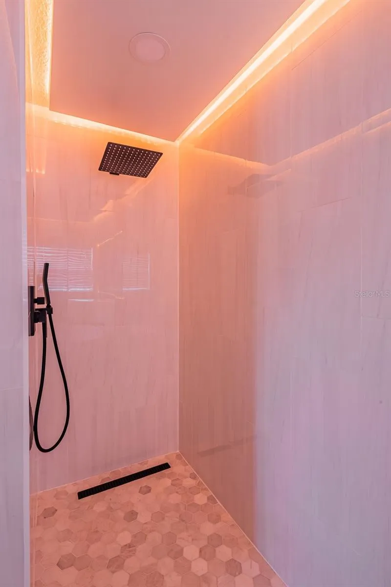 Completely gutted and rebuilt in 2022 with an investment of approximately $32,000, the primary bathroom includes a floating quartz double vanity, illuminated mirrors, an oversized walk in rain shower, multiple shower fixtures and lighted niches.