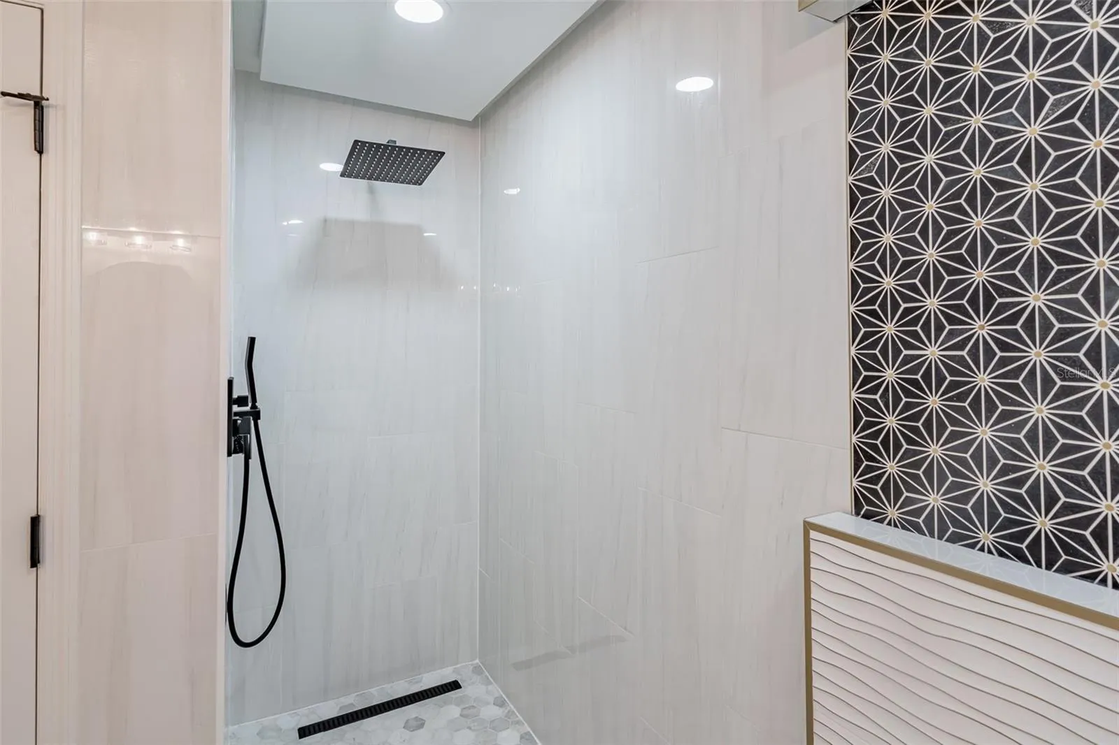 Completely gutted and rebuilt in 2022 with an investment of approximately $32,000, the primary bathroom includes a floating quartz double vanity, illuminated mirrors, an oversized walk in rain shower, multiple shower fixtures and lighted niches.