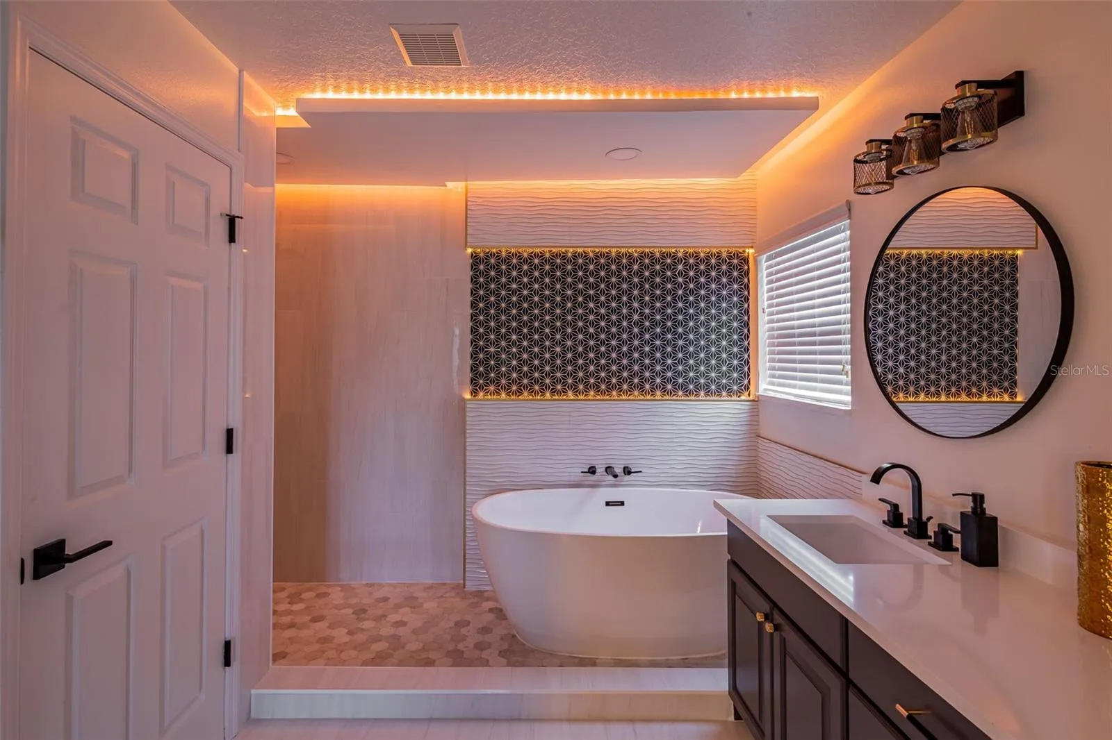 Completely gutted and rebuilt in 2022 with an investment of approximately $32,000, the primary bathroom includes a floating quartz double vanity, illuminated mirrors, an oversized walk in rain shower, multiple shower fixtures and lighted niches.