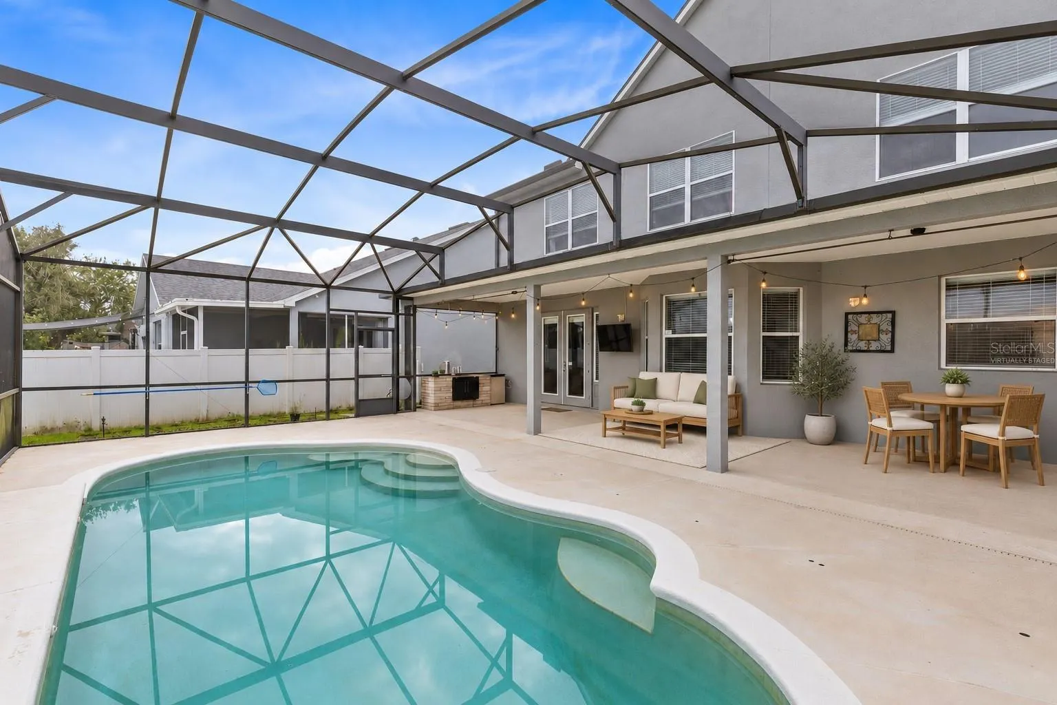 Virtually Staged: Outside, the covered lanai and screened pool overlook the pond, creating a peaceful setting with no immediate rear neighbors. The outdoor space also includes a built in grill and partially fenced backyard.