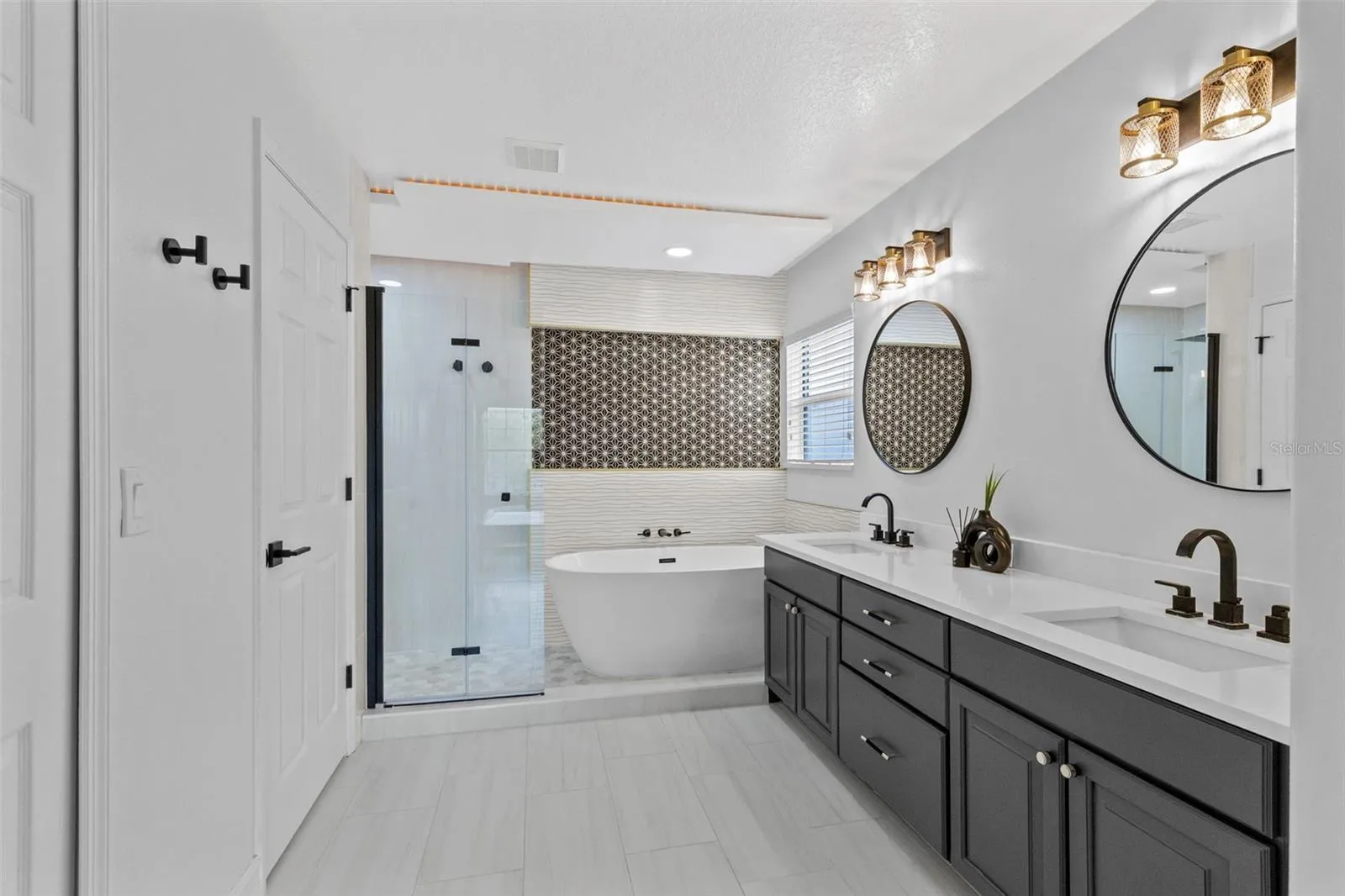 Completely gutted and rebuilt in 2022 with an investment of approximately $32,000, the primary bathroom includes a floating quartz double vanity, illuminated mirrors, an oversized walk in rain shower, multiple shower fixtures and lighted niches.