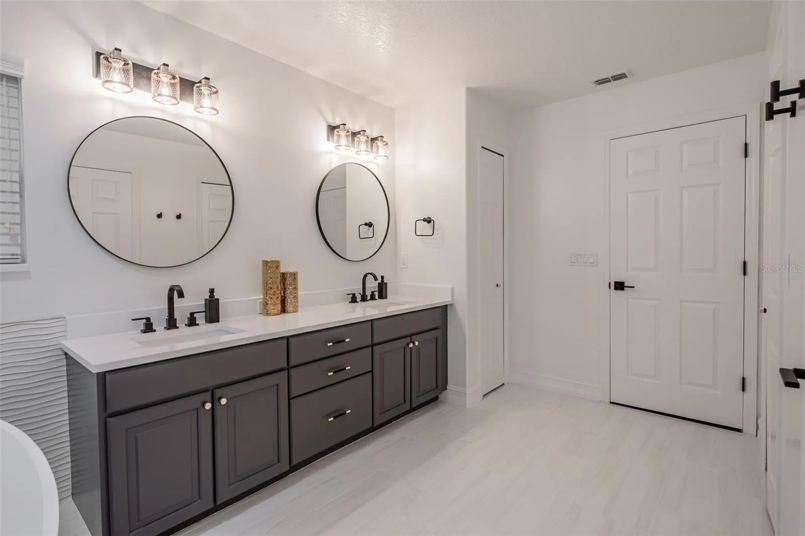 Completely gutted and rebuilt in 2022 with an investment of approximately $32,000, the primary bathroom includes a floating quartz double vanity, illuminated mirrors, an oversized walk in rain shower, multiple shower fixtures and lighted niches.