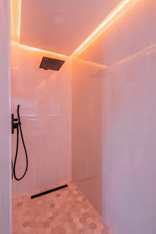 Completely gutted and rebuilt in 2022 with an investment of approximately $32,000, the primary bathroom includes a floating quartz double vanity, illuminated mirrors, an oversized walk in rain shower, multiple shower fixtures and lighted niches.
