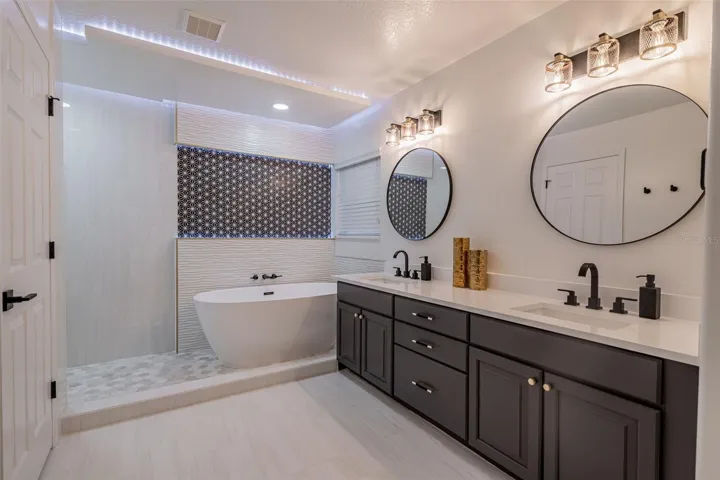 Completely gutted and rebuilt in 2022 with an investment of approximately $32,000, the primary bathroom includes a floating quartz double vanity, illuminated mirrors, an oversized walk in rain shower, multiple shower fixtures and lighted niches.