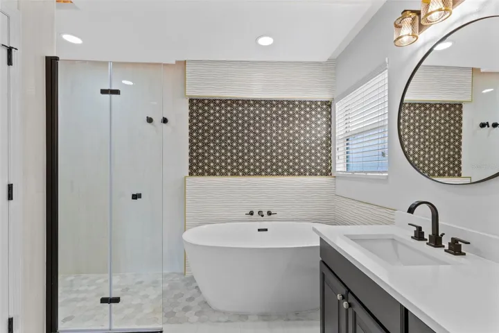 Completely gutted and rebuilt in 2022 with an investment of approximately $32,000, the primary bathroom includes a floating quartz double vanity, illuminated mirrors, an oversized walk in rain shower, multiple shower fixtures and lighted niches.