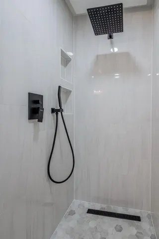 Completely gutted and rebuilt in 2022 with an investment of approximately $32,000, the primary bathroom includes a floating quartz double vanity, illuminated mirrors, an oversized walk in rain shower, multiple shower fixtures and lighted niches.