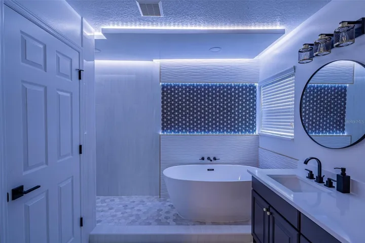 Completely gutted and rebuilt in 2022 with an investment of approximately $32,000, the primary bathroom includes a floating quartz double vanity, illuminated mirrors, an oversized walk in rain shower, multiple shower fixtures and lighted niches.