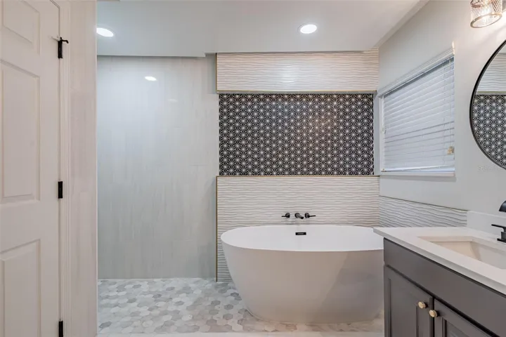 Completely gutted and rebuilt in 2022 with an investment of approximately $32,000, the primary bathroom includes a floating quartz double vanity, illuminated mirrors, an oversized walk in rain shower, multiple shower fixtures and lighted niches.