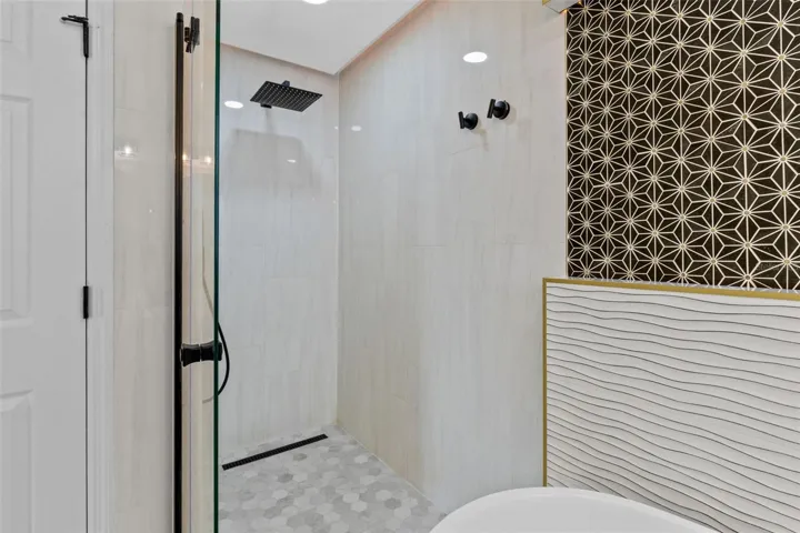 Completely gutted and rebuilt in 2022 with an investment of approximately $32,000, the primary bathroom includes a floating quartz double vanity, illuminated mirrors, an oversized walk in rain shower, multiple shower fixtures and lighted niches.