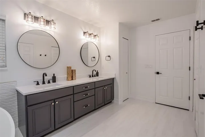 Completely gutted and rebuilt in 2022 with an investment of approximately $32,000, the primary bathroom includes a floating quartz double vanity, illuminated mirrors, an oversized walk in rain shower, multiple shower fixtures and lighted niches.