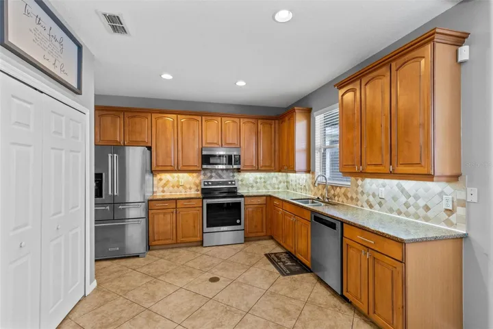 The kitchen features granite countertops, stainless steel appliances, solid wood cabinetry, a stone backsplash and pantry storage.