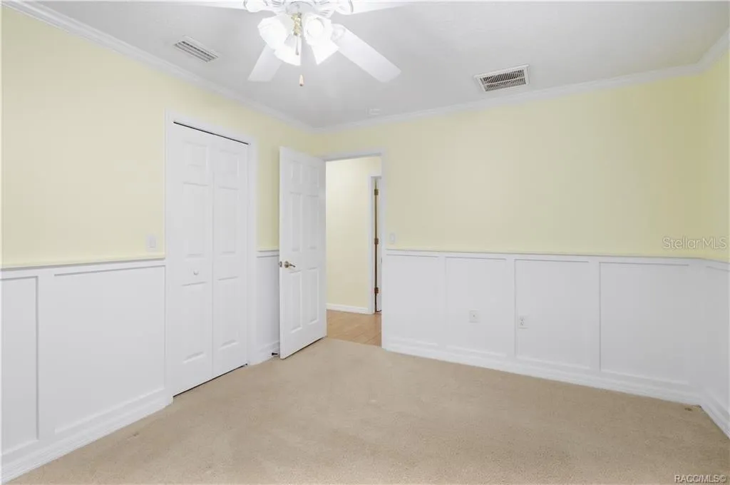 Additional Guest Bedroom – Spacious room with crown molding, ceiling fan, closet and decorative wall molding/wainscoting.