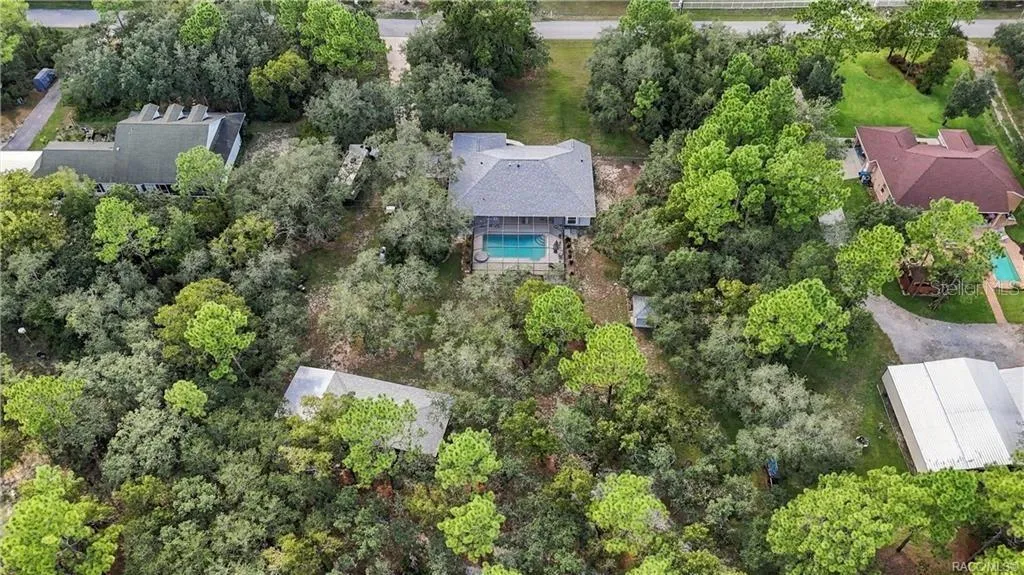 THE BIG PICTURE – Aerial view showcases the home, oversized screened pool, detached garage/outbuilding and expansive property.