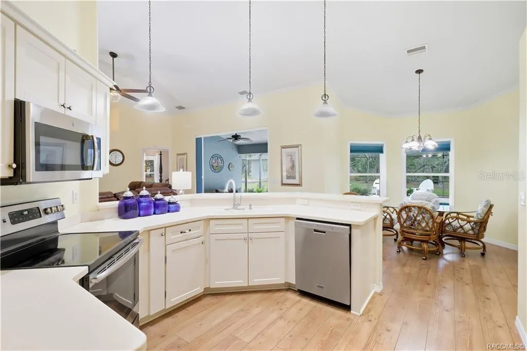 Kitchen &amp; Kitchen Nook Area – Open kitchen featuring abundant cabinetry, corian countertops, breakfast bar, NEWER stainless-steel appliances &amp; adjoining dining area.