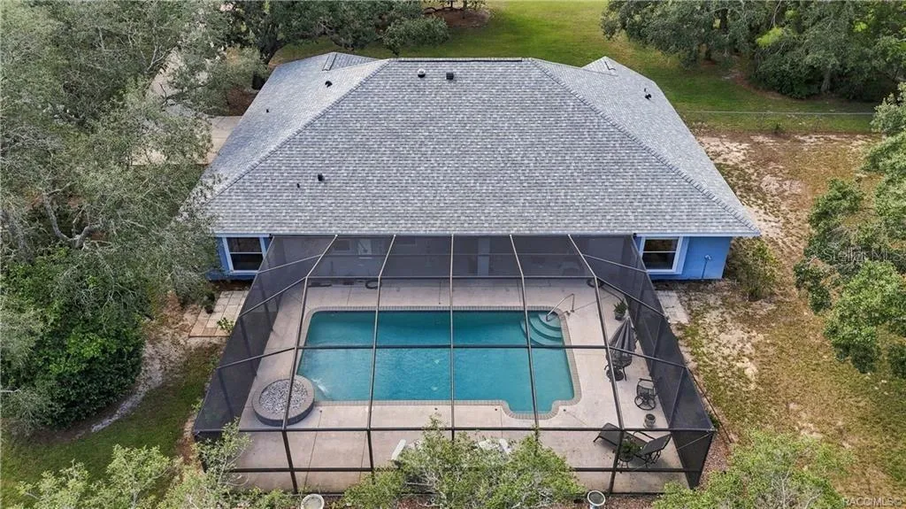 POOL LIVING FROM ABOVE – Aerial view showcases the impressive size of the screened pool enclosure, expansive pool deck &amp; covered outdoor living area.