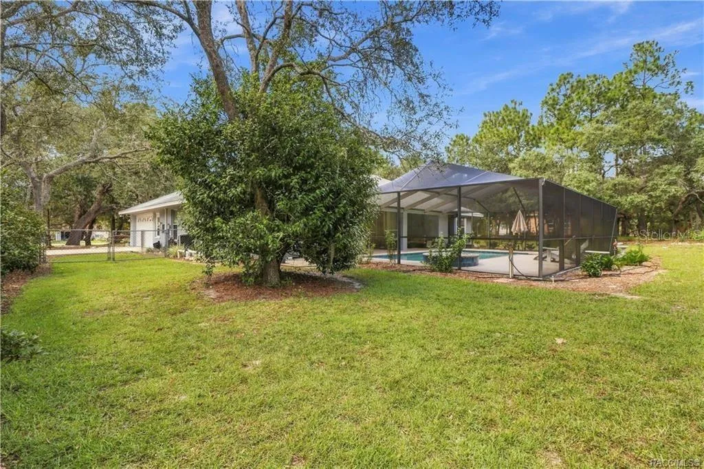 ROOM TO SPREAD OUT – Spacious backyard surrounded by mature trees with the screened pool area just steps from the home.