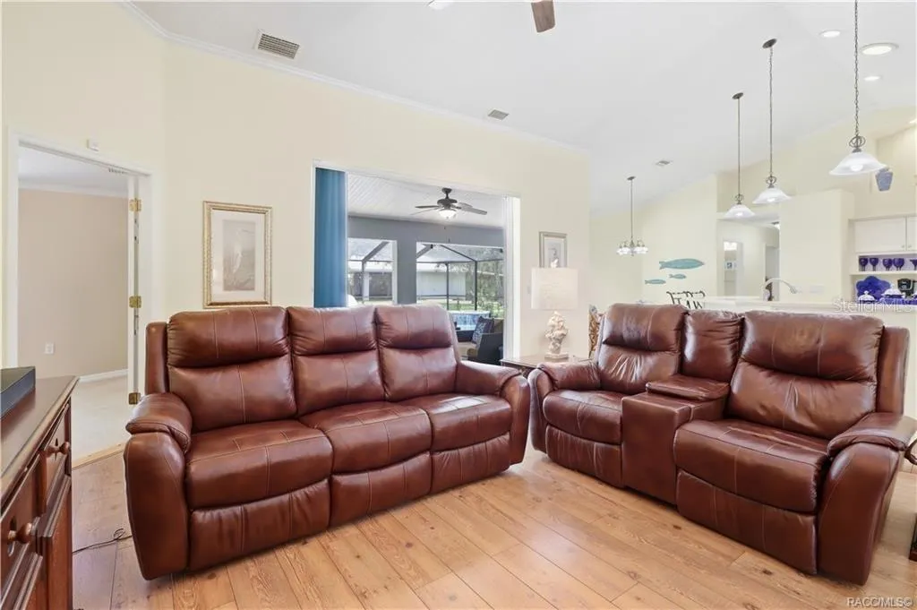 Open Living Area – Spacious living room highlighting the open flow to the kitchen, dining areas &amp; screened pool/lanai.