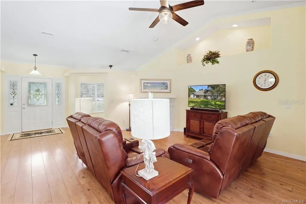 Living Room – Spacious living area with vaulted ceiling, crown molding, wood-look flooring, ceiling fan &amp; open layout.