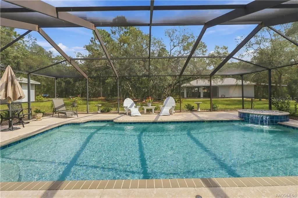 Screened Pool 14 x24 &amp; Decorative Spillover Waterfall – Expansive screened pool area featuring a large salt water swimming pool, waterfall with spillover feature and spacious pool deck.
