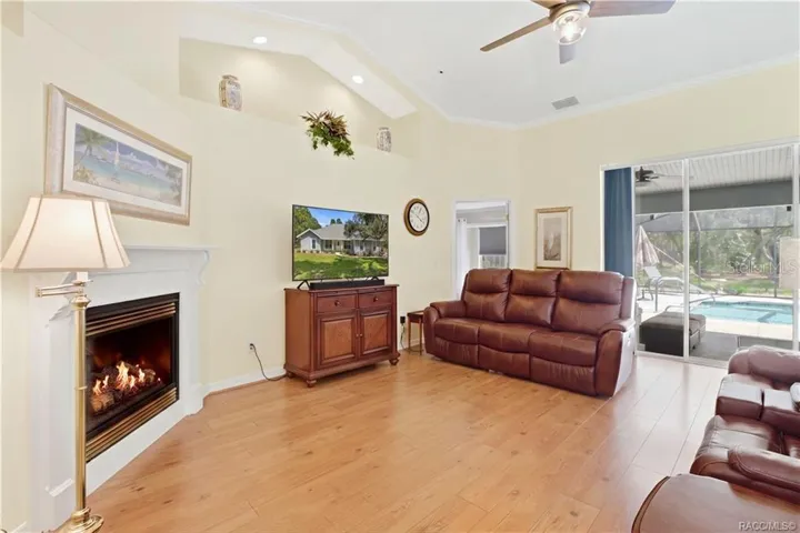 Living Room / Pool View – Open living space with gas fireplace and large sliding glass doors providing a direct view into the screened pool area.