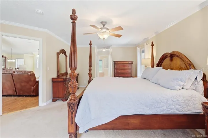 Primary Bedroom – Spacious primary suite with crown molding, ceiling fan, neutral finishes and private access toward the ensuite bath.