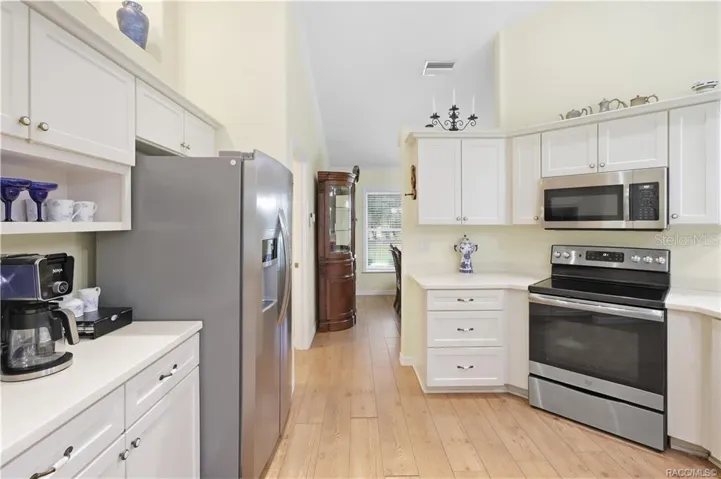 Kitchen – Bright kitchen with abundant white cabinetry, stainless-steel appliances, extensive counter space &amp; laminate flooring.