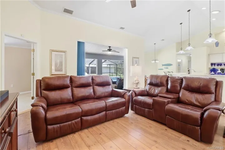 Open Living Area – Spacious living room highlighting the open flow to the kitchen, dining areas &amp; screened pool/lanai.