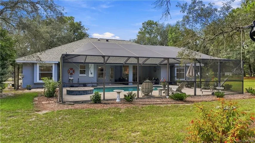 A BACKYARD BUILT FOR FLORIDA LIVING – Full view of the oversized screened pool enclosure extending across the rear of the home.