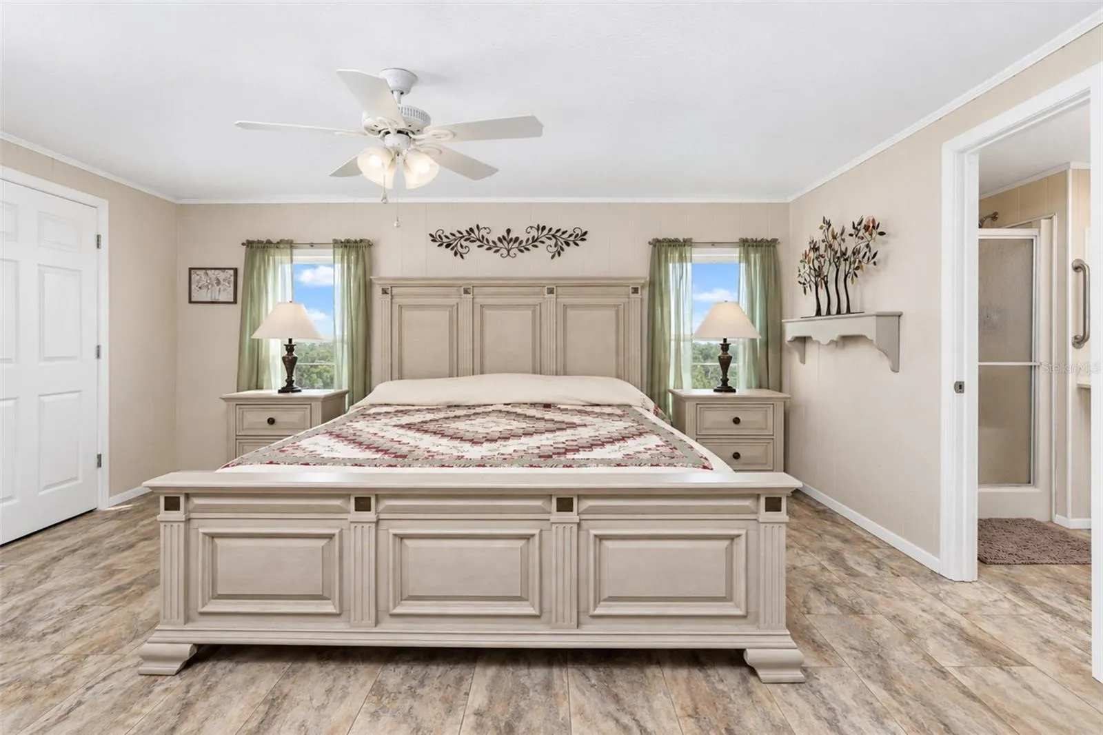 The primary bedroom features LVP flooring, a ceiling fan and a huge walk-in closet.