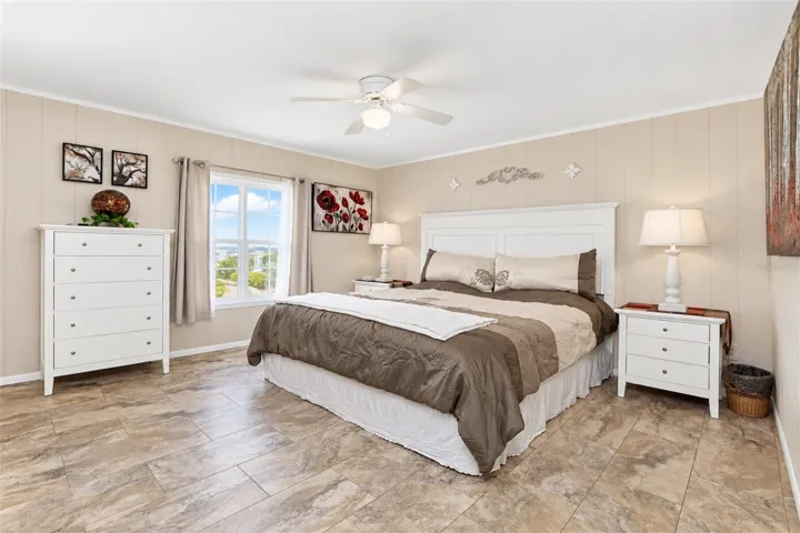The spacious guest bedroom has LVP flooring and a ceiling fan.