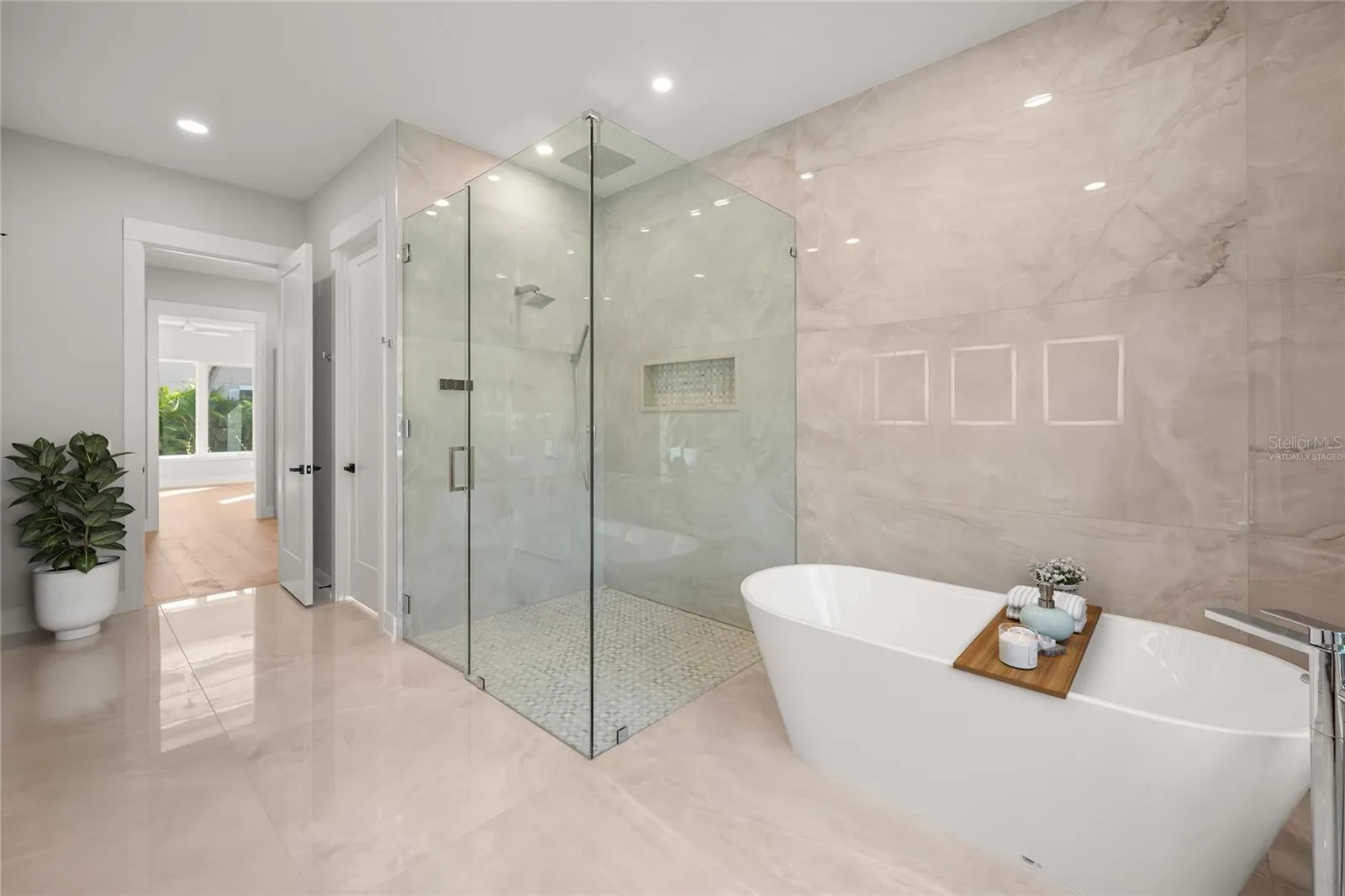 Virtually staged primary suite features a luxurious spa-inspired bath with soaking tub, spacious walk-in shower, designer tile, beautifully curated finishes, and a generous walk-in closet.