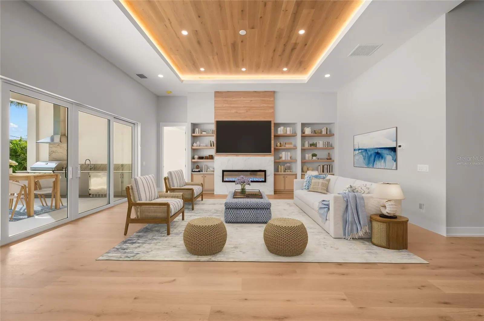 Virtually staged family room featuring a modern fireplace and custom built-ins, opening seamlessly to the outdoor entertaining area.