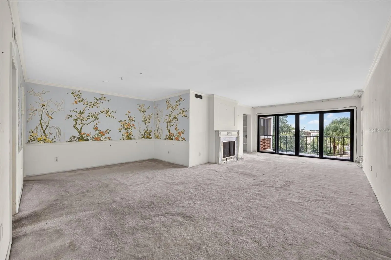 A spacious, light-filled living and dining area features a classic fireplace, walls of glass, and beautiful treetop views, offering endless possibilities to create a stunning modern retreat.