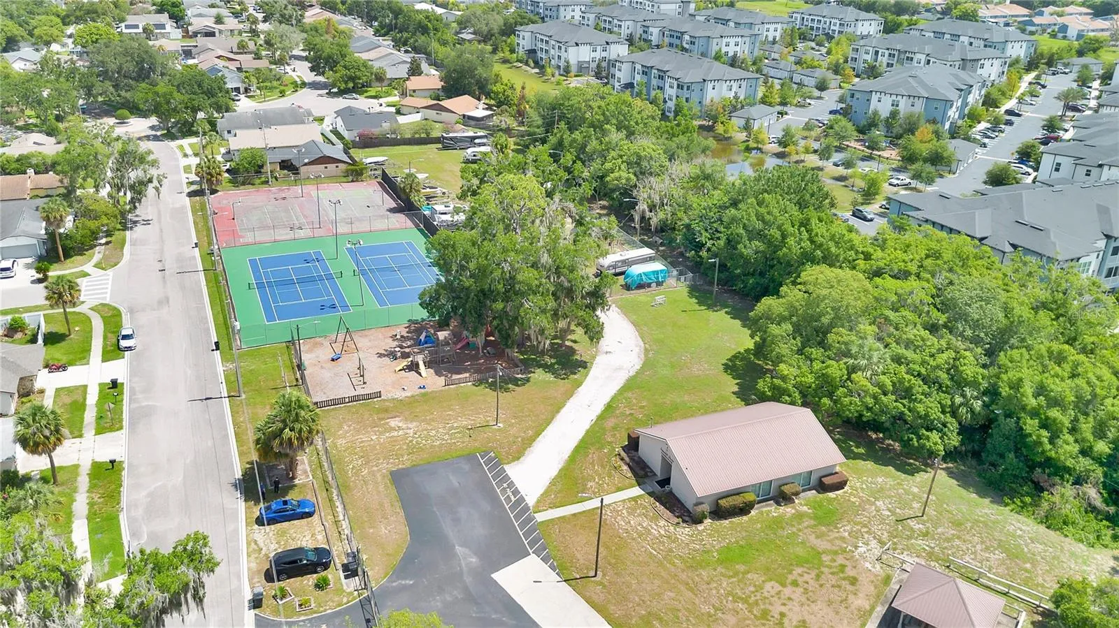 Aerial view of the clubhouse, Playground, Pickle Ball and Tennis Courts, Basketball Courts, RV Storage and Dog Run