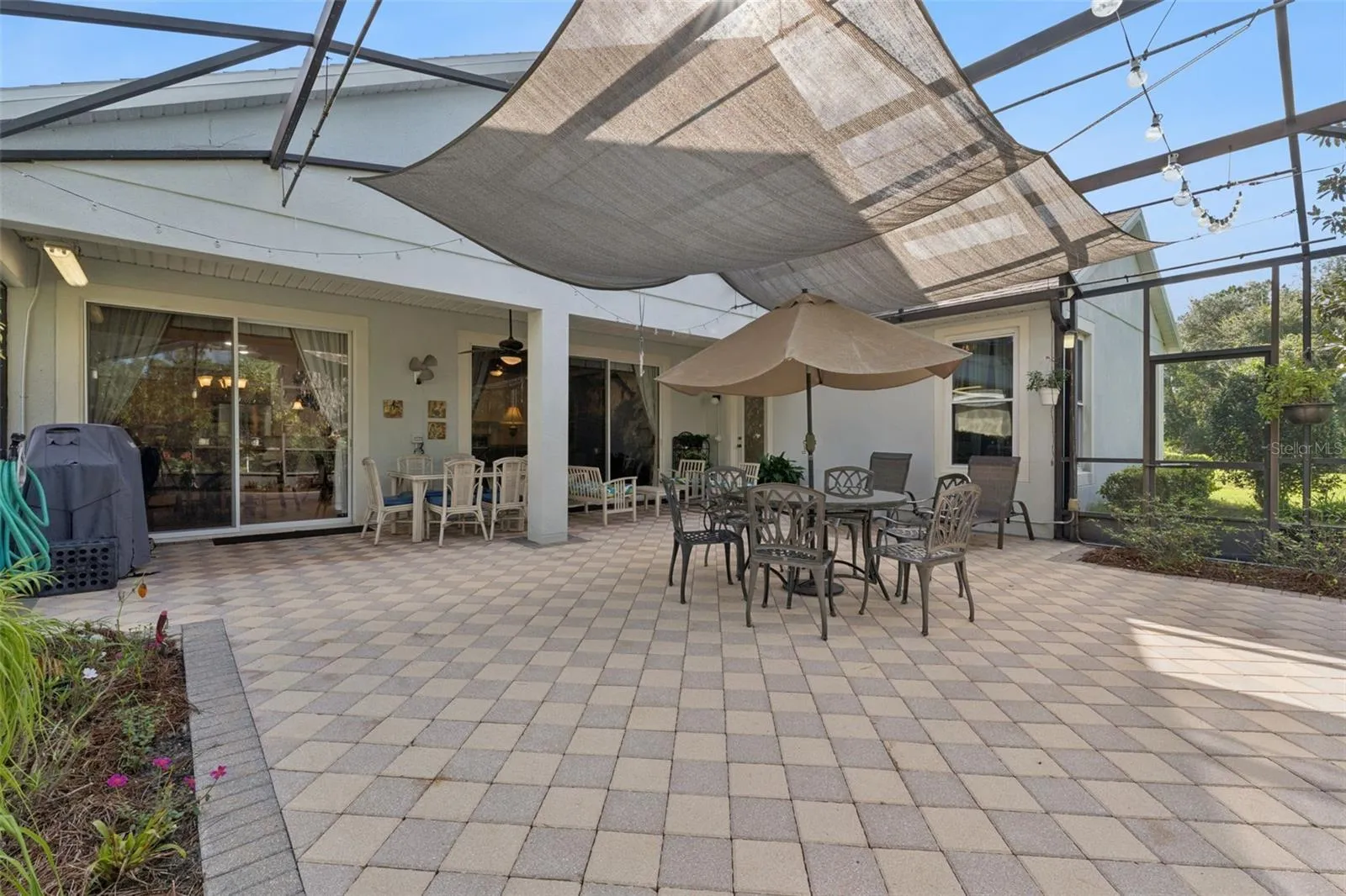 Screen enclosed covered patio w/ brick pavers, an awning &amp; lighting