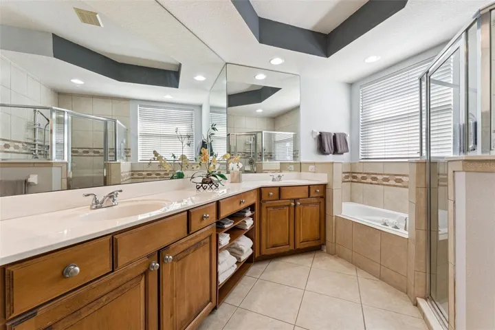 11'6" x 11' Primary Bathroom w/ a raised height vanity, dual sinks, corner soaking tub &amp; glass enclosed walk-in shower