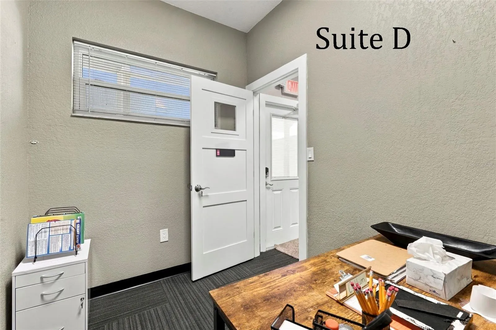 Suite D has a high window and is located near the hall restroom and Covered Patio Break Common Area
