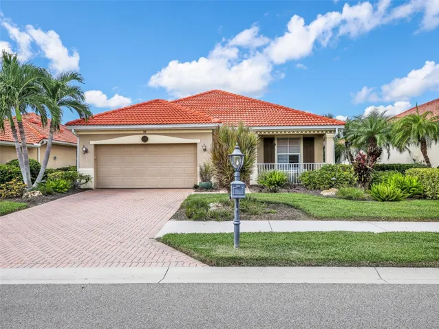 Attractive curb appeal with mature landscaping, a paver driveway, and two-car gara