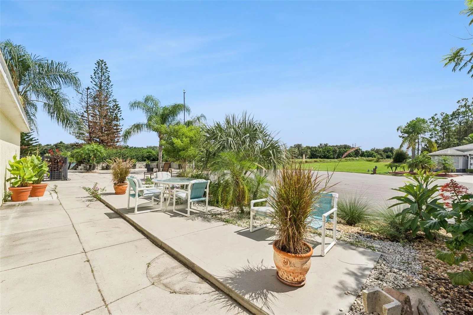 A concrete side patio surrounded by beautiful Tabebuia trees creates another inviting outdoor gathering space